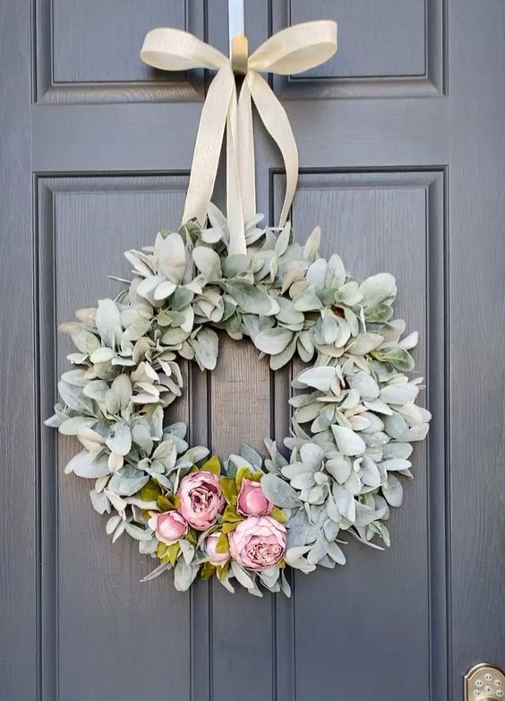 a lovely and simple spring wreath of pale greenery, pink faux blooms and a neutral ribbon bow is chic