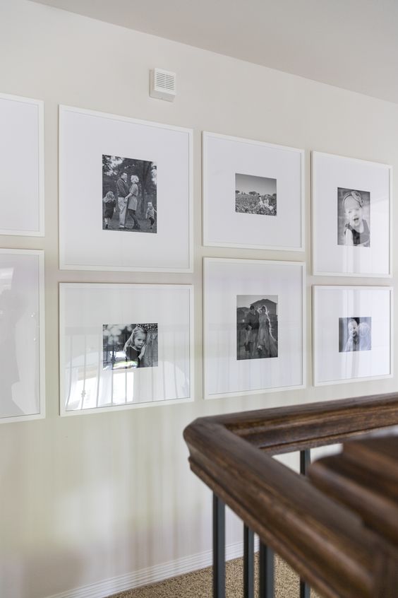 a modern grid gallery wall with white frames and black and white family pics plus white matting is fresh
