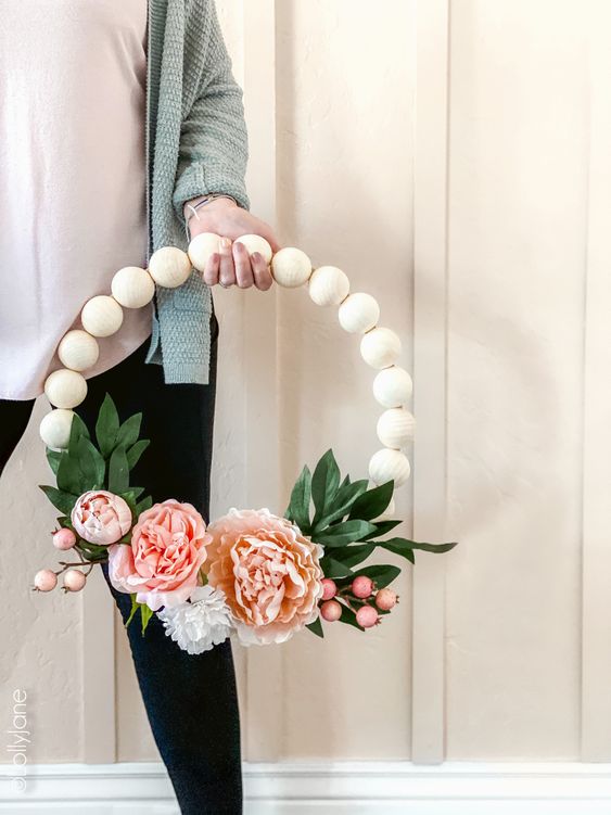 A pretty spring wreath of large wooden beads, pink blooms and berries and faux leaves is a simple and long lasting decoration