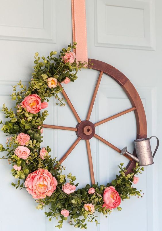 31 a rustic spring wreath of a large wooden wheel, artificial greenery and pink peonies and a little watering can is very cool