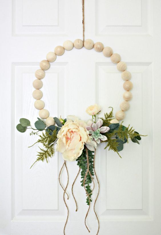 a wooden ball hoop wreath with artificial greenery, succulents, peachy blooms and some twine hanging down