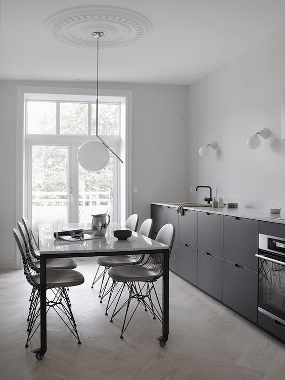 a Scandinavian black one wall kitchen with a white coutnertop and black fixtures plus some sconces and a pendant lamp