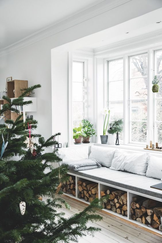 a Scandinavian space with a bow window and a windowsill bench with firewood storage, potted plants and much natural light