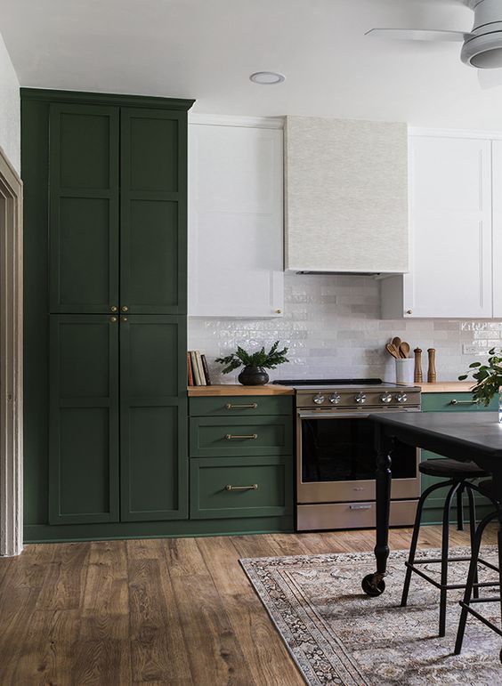 a beautiful dark green and white kitchen in vintage style, with a neutral hood and butcherblock countertops is chic