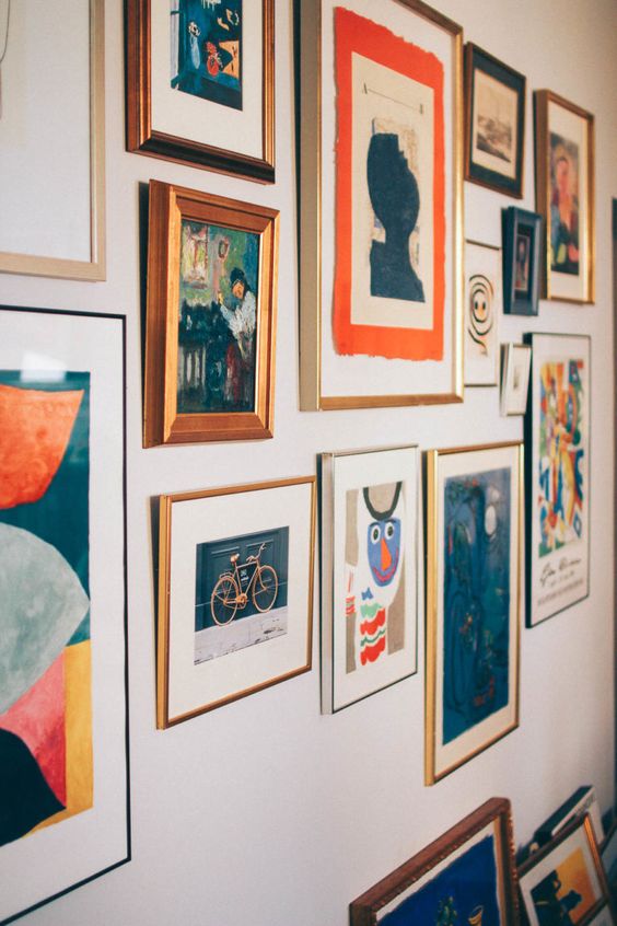 a bold gallery wall with a free shape, mismatching frames and colorful paintings, prints and posters with a vintage feel