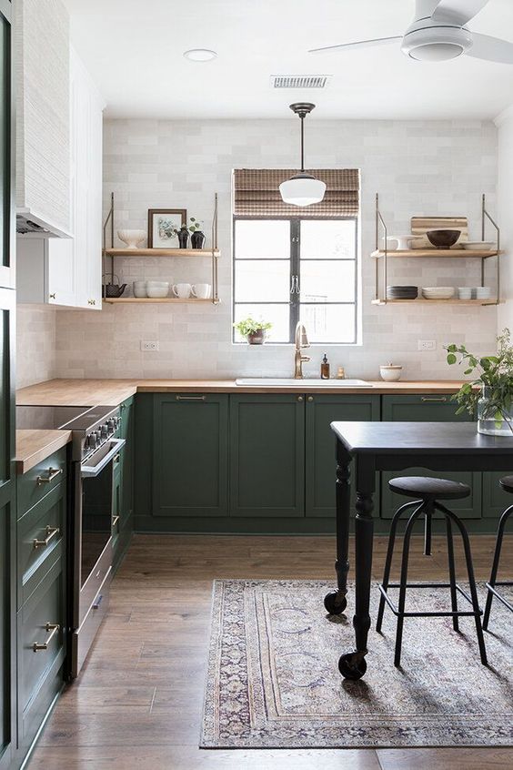 A bold green and white L shaped kitchen with butcherblock countertops, open shelves and brass touches is very cozy
