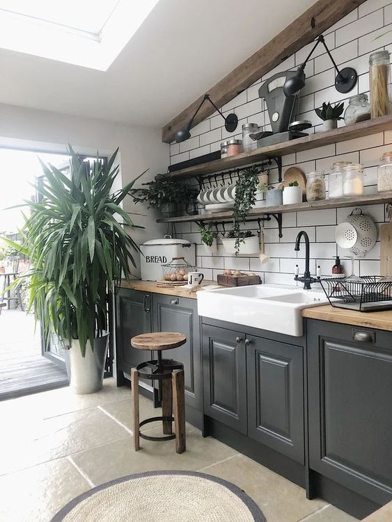 a bold modern kitchen in black, butcherblock countertops, a white subway tile backsplash and potted greenery plus open shelves