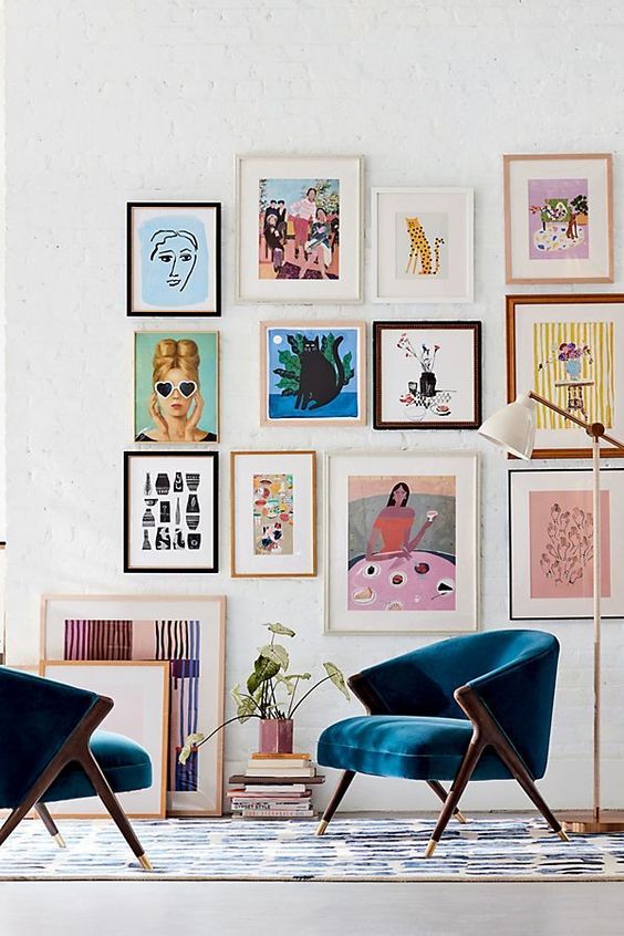 a bright and colorful gallery wall with mismatching frames, colorful posters and artworks and fun primitive artworks
