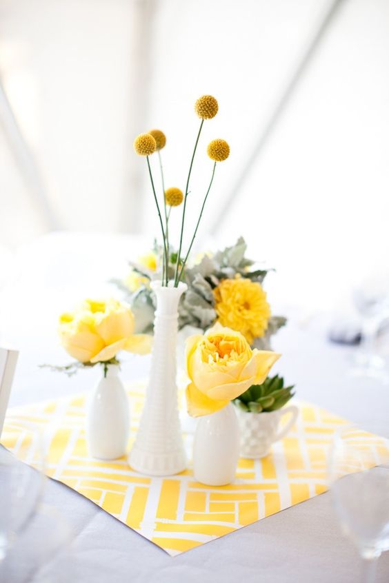 a bright and fun spring centerpiece with milk vases, yellow blooms, succulents and greenery