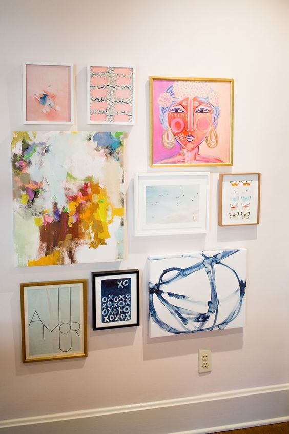 a bright gallery wall with mismatching frames and bright artworks is a bold and cool idea for a bright space