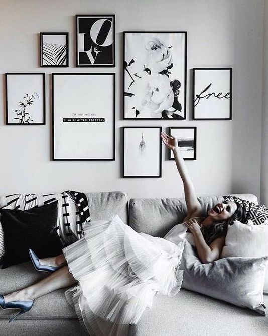 a chic black and white free form gallery wall with thin black frames and black and white art just wows