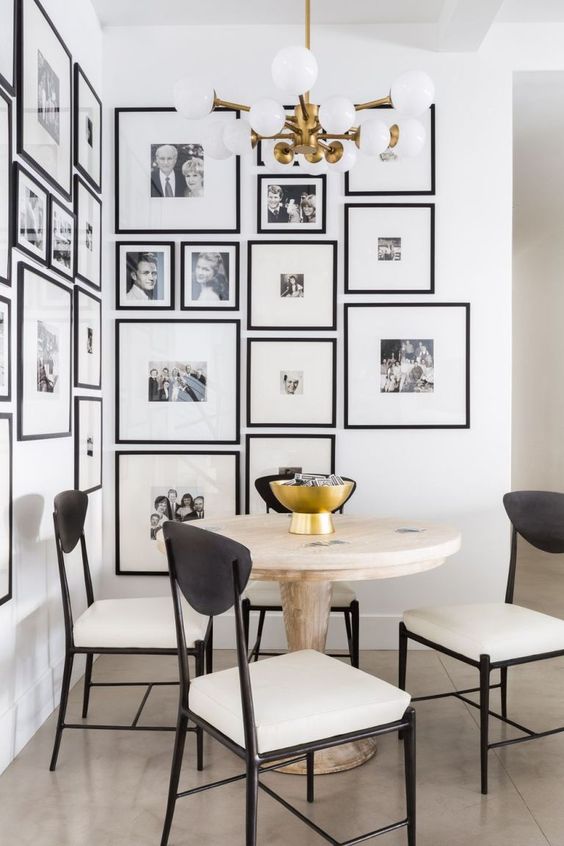 a chic gallery wall with black and white photos and in matching black frames accents this dining corner