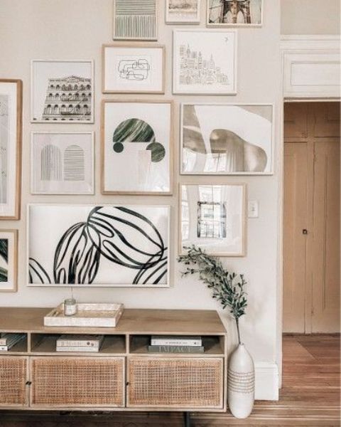 a chic gallery wall with mismatching blonde wood and white frames and muted color art and prints is stylish
