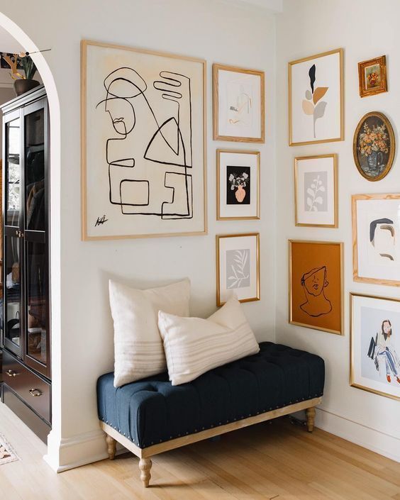 a chic gallery wall with mismatching wood and gold frames and various abstract art to accent a little nook
