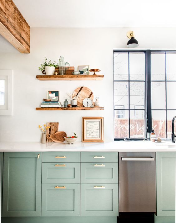 a chic green kitchen in farmhouse style, a white stone countertop and open shelves, wooden beams and a window with a black frame