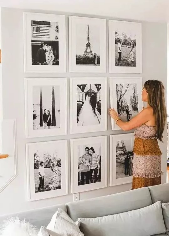 a chic grid gallery wall with matching white frames and black and white family pics is cool and very elegant