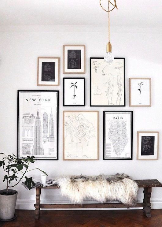 a chic monochromatic gallery wall with black and blonde wood frames, black and white artworks and prints
