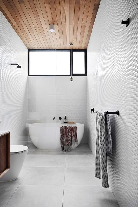 a contemporary bathroom with penny and large scale tiles, a wooden ceiling with a clerestory window and an oval tub
