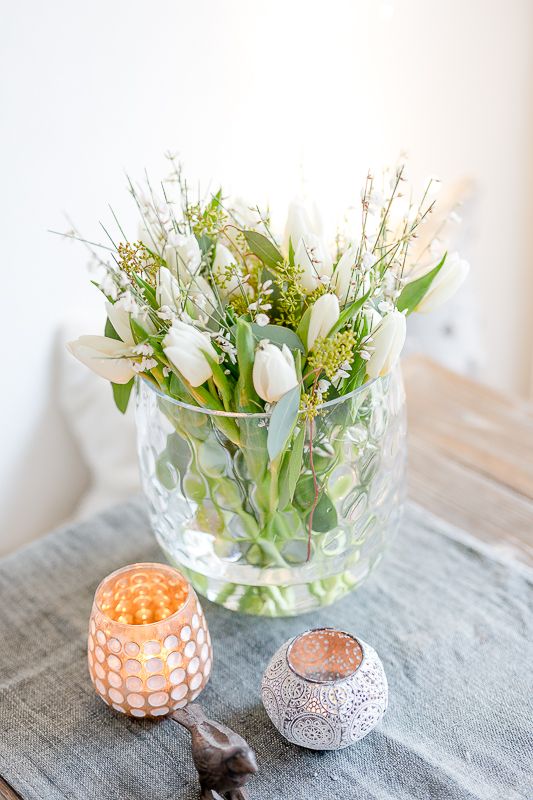a cool clear vase with greenery and white blooms is a chic and simple spring arrangement or centerpiece to rock