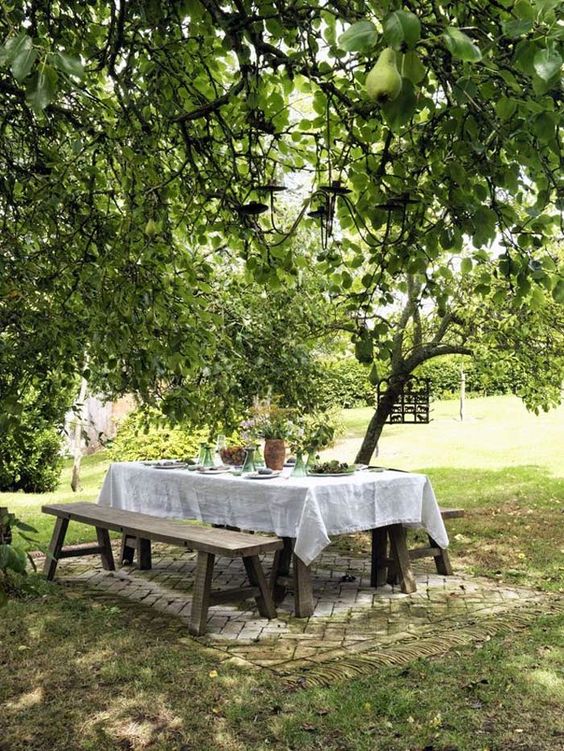 a cozy and simple dining space right in the garden, with simple wooden dining furniture – a table and benches