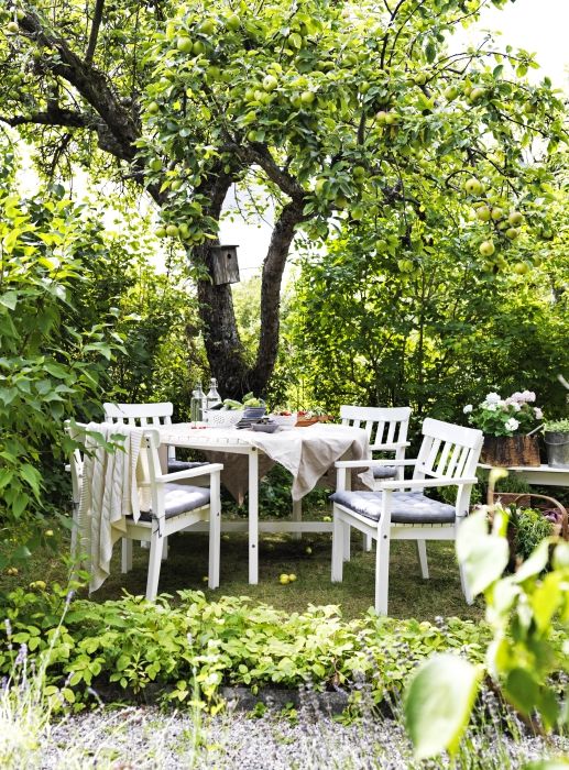 a cozy dining area done with IKEA furniture under the trees, with blooms and greenery around is cool
