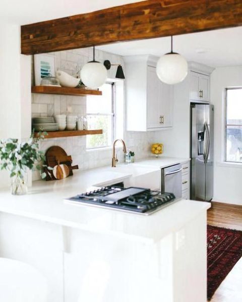 a cozy white farmhouse kitchen with a white marble tile backsplash and a wooden beam is very welcoming
