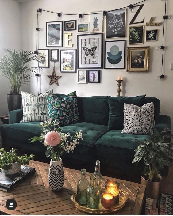 a creative gallery wall with black and gilded frames, black, white and green prints and artworks, lights, a monogram and a star of wood