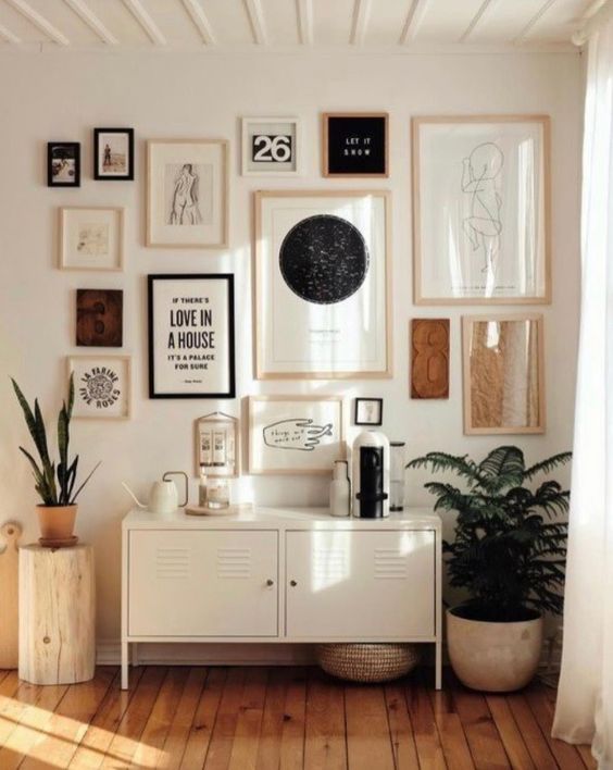 a creative gallery wall with black and white artworks in mismatching blonde wood frames and a couple black ones