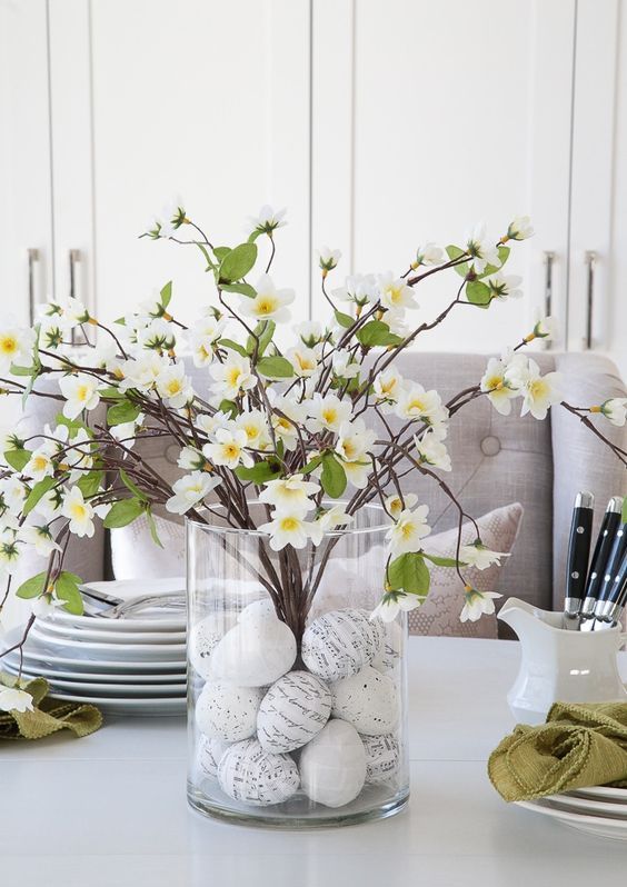 a cute spring to Easter centerpiece of a clear vase with graphic eggs and faux blooming branches is lovely