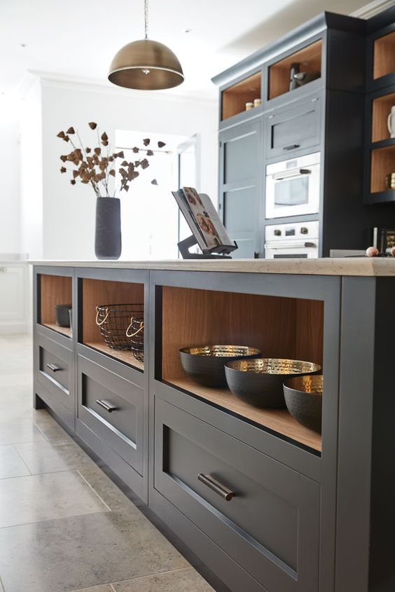 a dark grey shaker style kitchen with open compartments, butcherblock countertops, a metal pendant lamp and built-in appliances