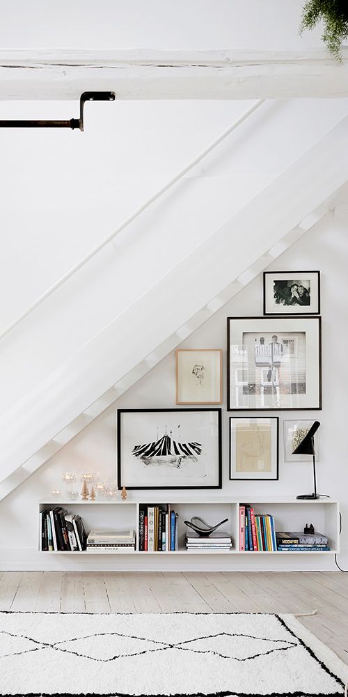 a free form gallery wall on the staircase, with mismatching frames and black and white artworks and photos
