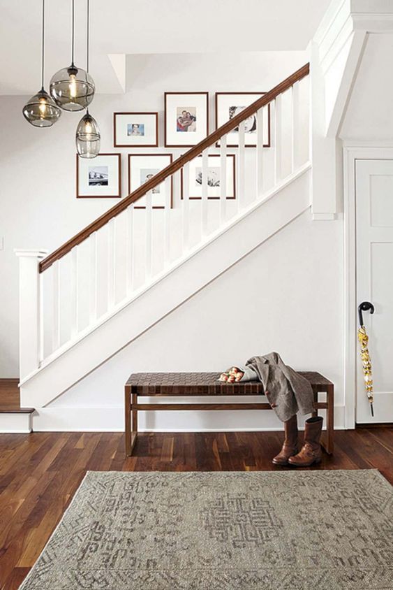 a free form gallery wall with colored family photos is a fresh and cool idea to spruce up the space over the stairs