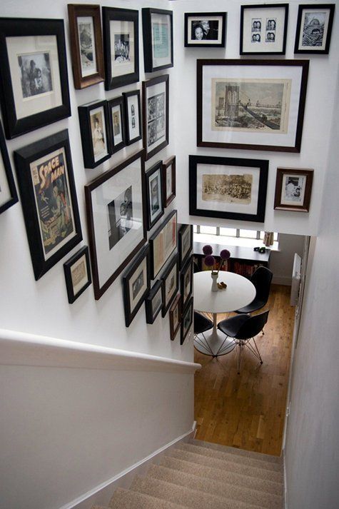 a free form gallery wlal over the staircase with mismatching frames and various types of retro and vintage art
