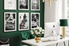 a gorgeous emerald home office with a white desk, an emerald chair and a bench, a black and white gallery wall and a gold chandelier and a table lamp