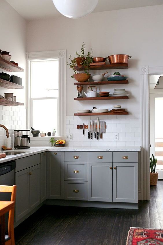 A grey boho L shaped kitchen with open shelves, a white stone countertop and a white tile backsplash plus greenery