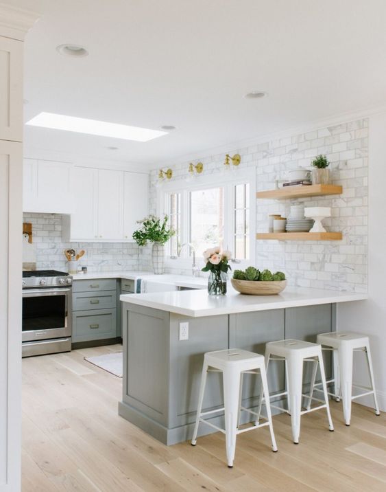 a grey farmhouse kitchen with a white marble tile backsplash and white tone countertops plus a skylight