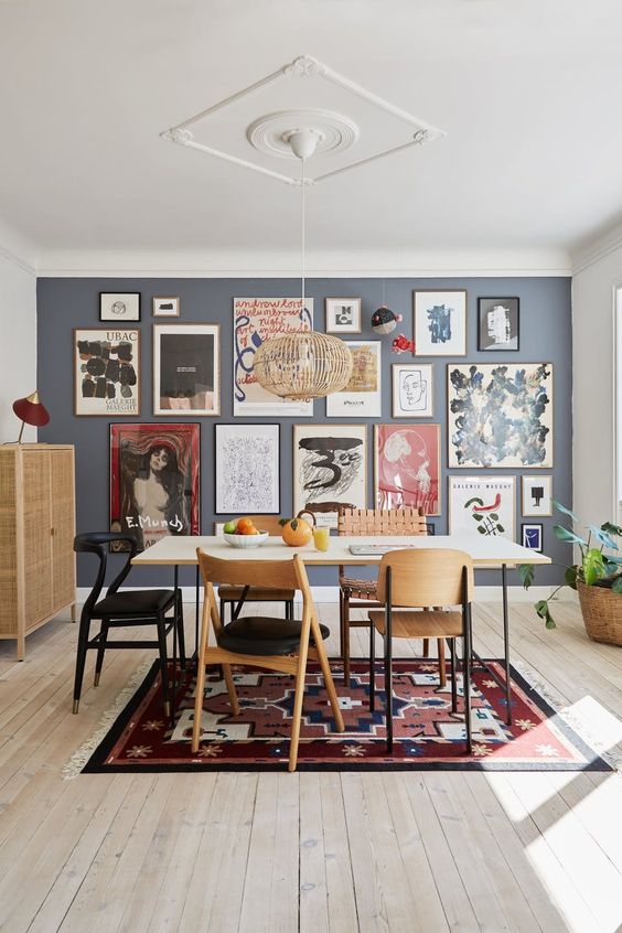 a large and bold free form gallery wall with thin frames and colorful art, mostly abstract, takes over the whole space