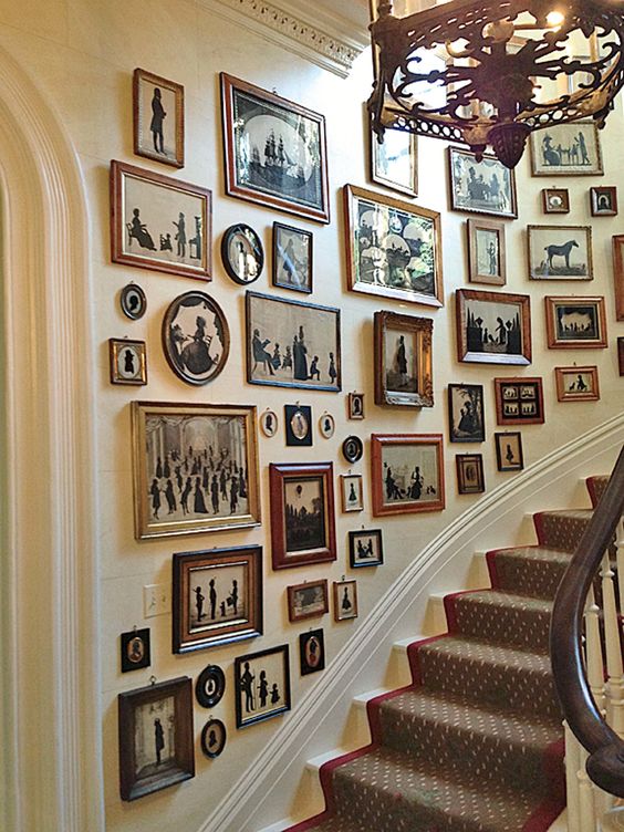 a large gallery wall with mismatching vintage frames and black and white artworks with a strong elegant vintage feel