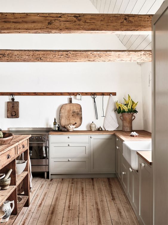 a light grey kitchen with butcherblock countertops and wooden beams, a wooden kitchen island and a wooden floor