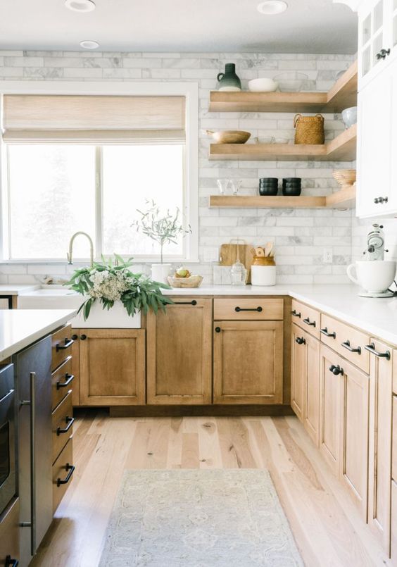 A light stained wooden kitchen with a marble tile backsplash and open floating shelves is a pretty rustic space