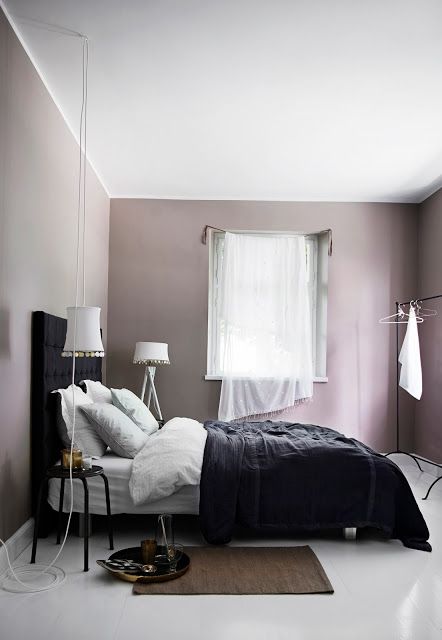a mauve Scandinavian bedroom with a black bed, black and white bedding, neutral curtains and white lamps