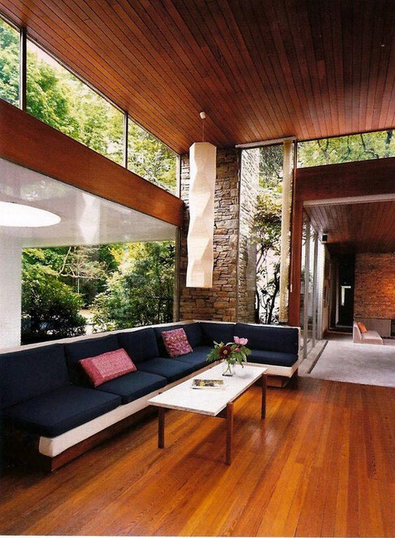 A mid century modern living room with a large sectional, a coffee table and clerestory windows and a glazed wall