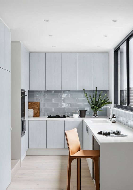 A minimal Nordic L shaped kitchen with glass tiles and a window with a view is a lovely idea