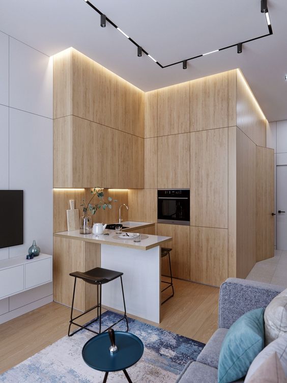 A minimalist blonde wood L shaped kitchen with built in lights and a tiny kitchen island is super cool