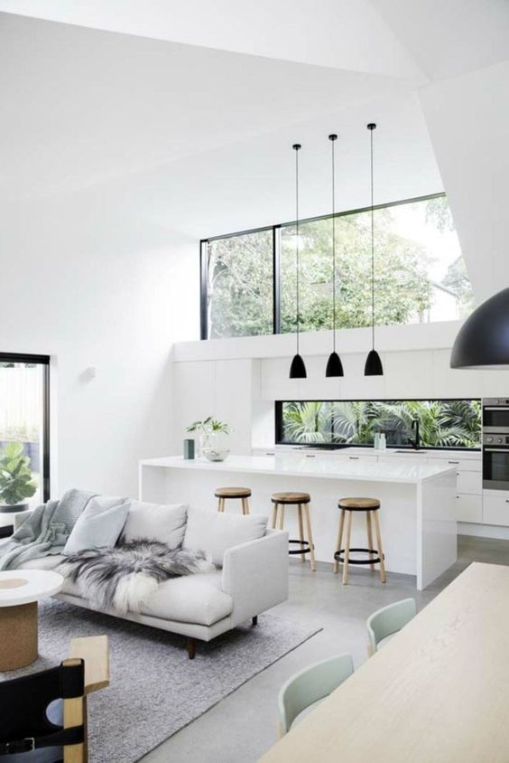 a minimalist tropical space in white and grey, with black touches for drama and with a large clerestory window for more light