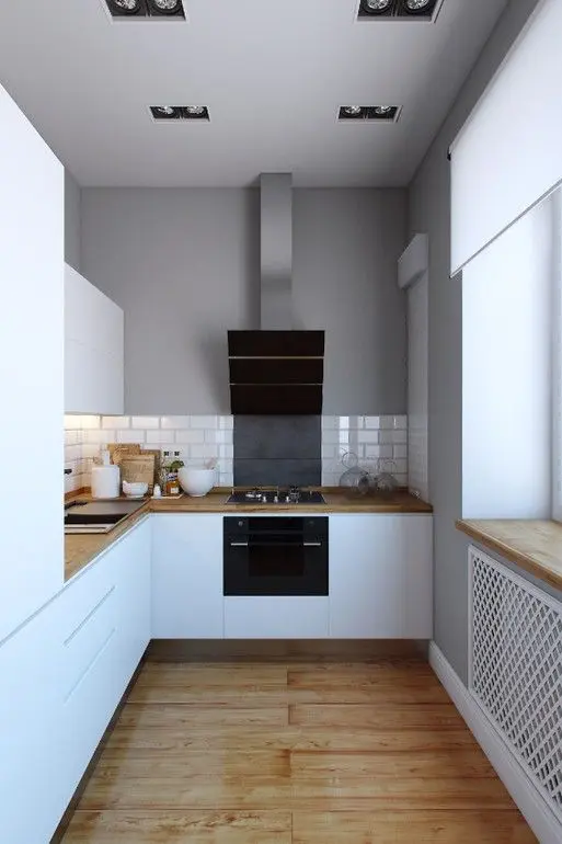 A minimalist white kitchen with butcherblock countertops, a white tile backsplash and built in appliances