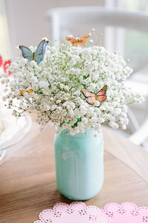 a mint colored jar with baby's breath and colorful paper butterflies is a chic and lovely idea for spring