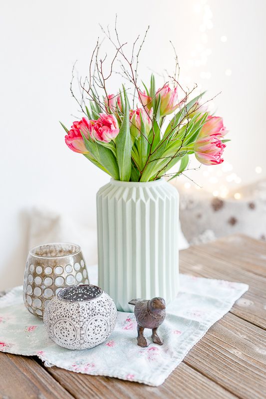 a mint green ribbed vase with pink tulips and twigs is a very chic and lovely decoration or centerpiece for spring