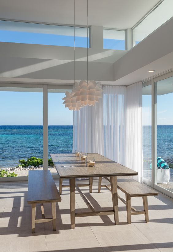 a modern beach house in white, with wooden furniture, pendant lamps and glazed walls plus clerestory windows