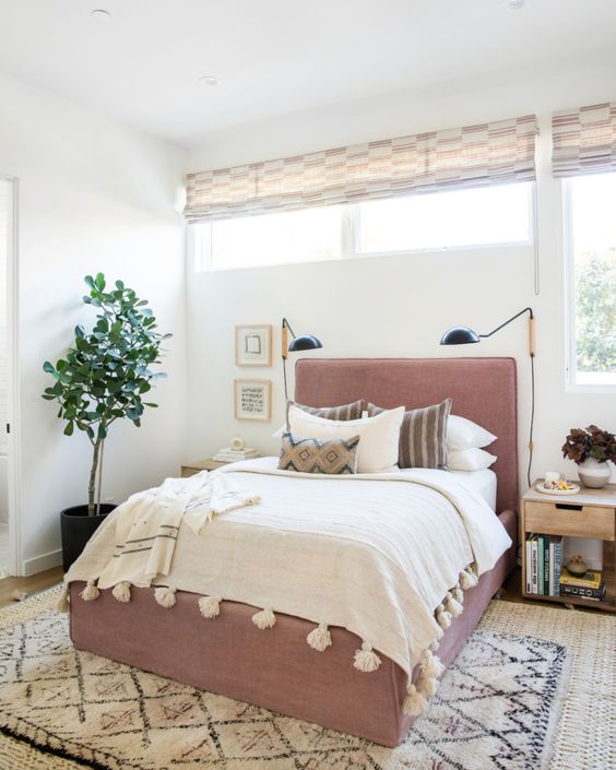 a modern bedroom with a window and a clerestory window, a mauve bed and sconces plus a potted plant